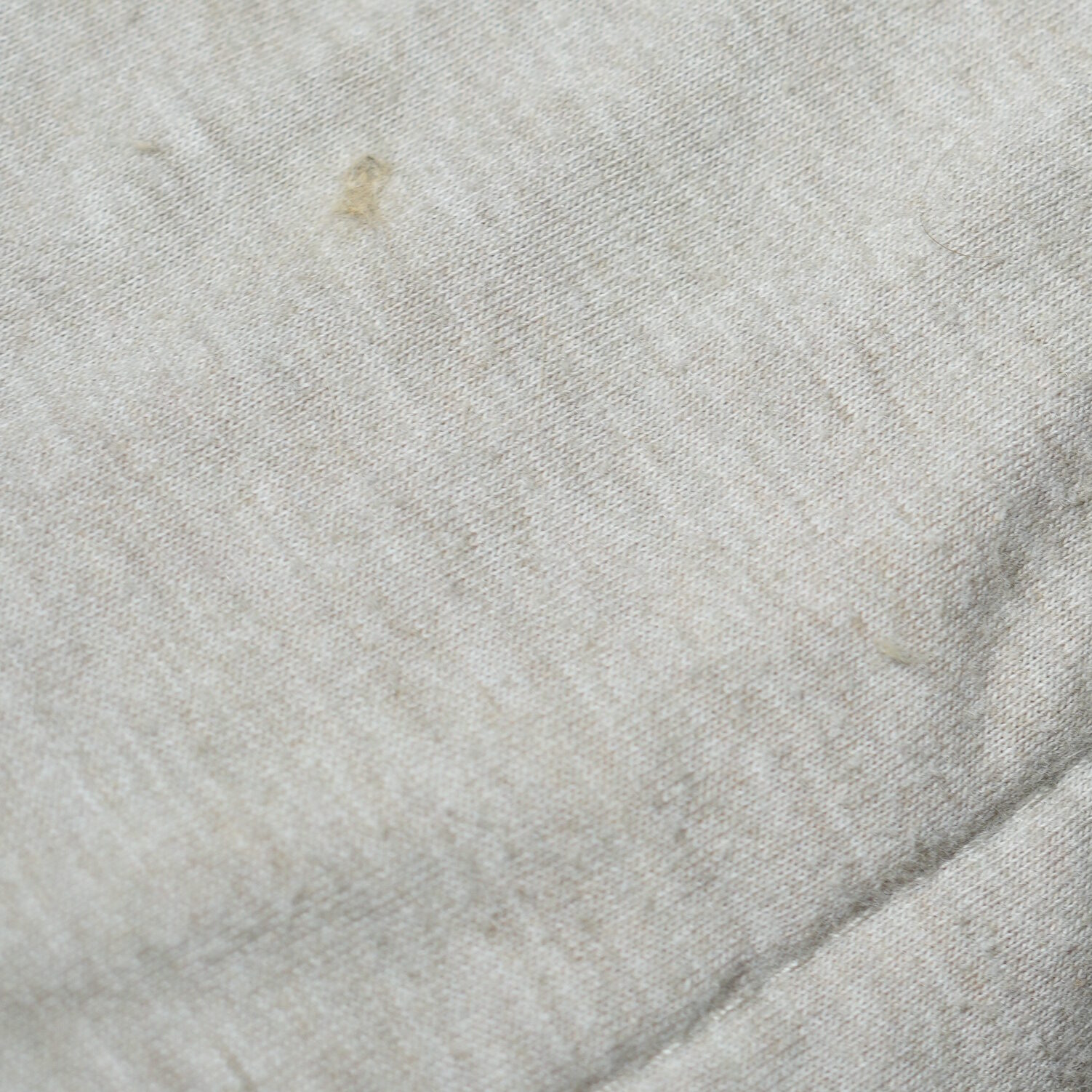 Macro close-up of cotton-poly sheets showing loose fibers, lifted ends, and embedded cat hair fragments