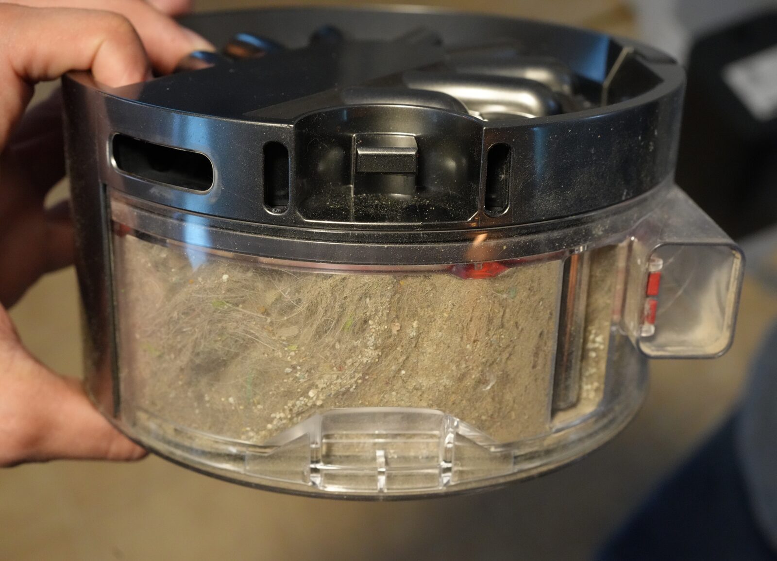 Felix holding the Dyson 360 Vis Nav dust bin packed with cat hair and litter after one cycle